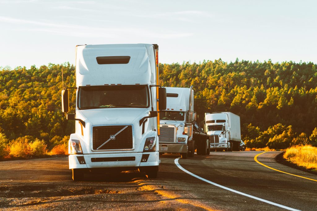 pexels photo 2199293 2199293 Three semi trucks driving on a highway through a forested landscape in Arizona.